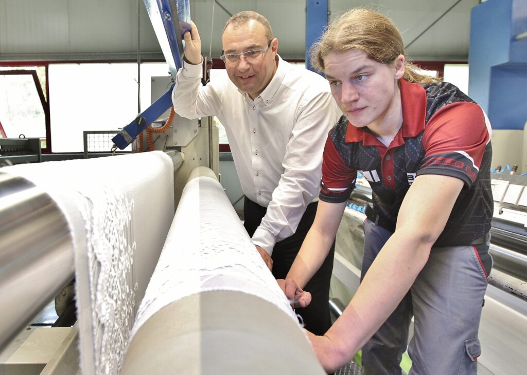Pfand Textil Geschäftsführer Holger Erth (links) und Mandy Tysar (rechts) am Auslauf der Spannmaschine mit einer Heimtextilie aus Plauener Spitze